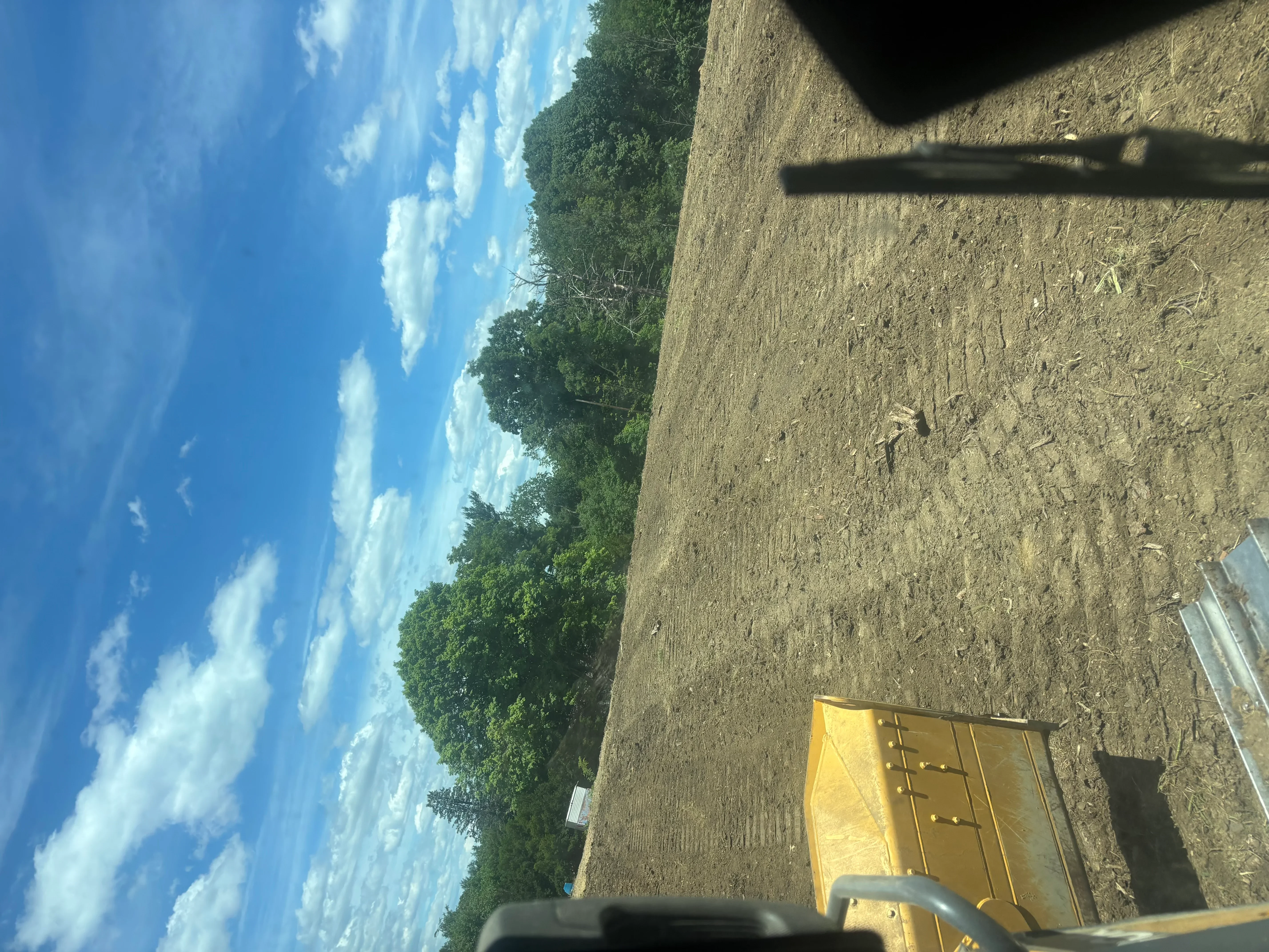 Cleared land lot with graded soil and retained trees along property edge